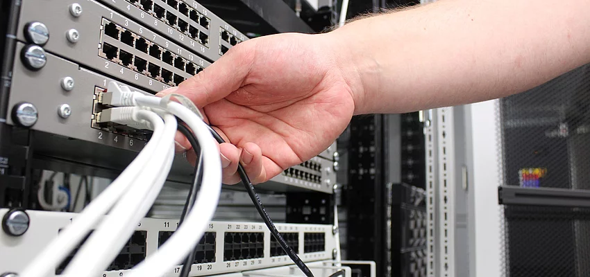 IT Serverraum Eine Hand greift nach einem Kabel an einem Server.