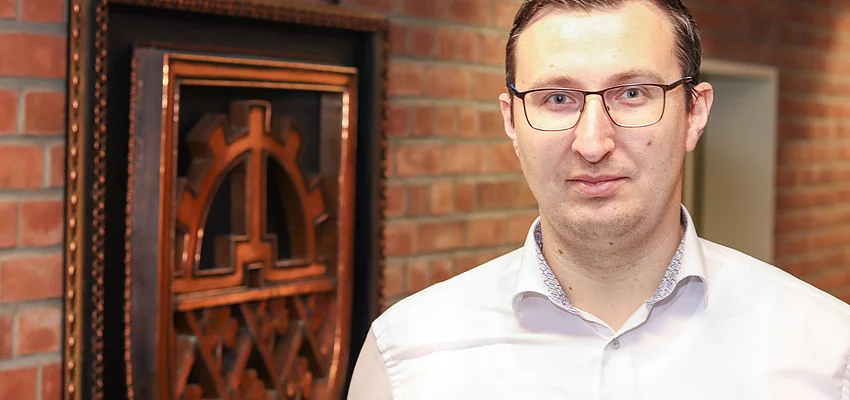 Bürgermeister Patrick Klose Bürgermeister Patrick Klose steht vor einem kupferfarbenen Glinder Wappen.