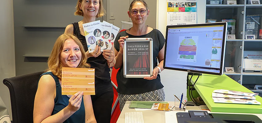 Vorverkauf für 'Theater im Forum' in der Stadtbücherei Glinde Drei Frauen stehen an einem Computerbildschirm auf dem der Saalplan eines Theaters zu sehen ist.