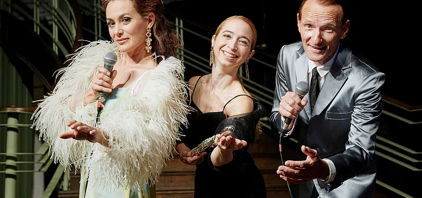 Szene aus Gazino Altinova Zwei Frauen und ein Mann im Gala-Outfit mit Mikrofonen in der Hand.